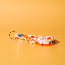 An orange and white stress reliever key chain featuring poppable buttons and a metal keyring.
