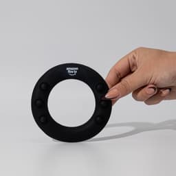 A hand holding a black silicon wrist disc with buttons and a logo at the top.