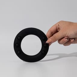 A black silicone wrist disc held by a hand, featuring several raised buttons around its edge.