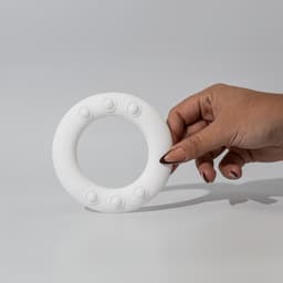 A hand holding a white silicone wrist disc with textured buttons, designed for promotional use.