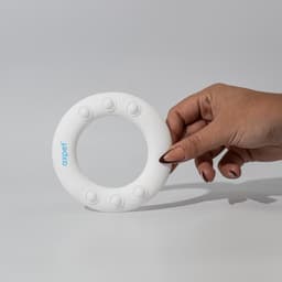 A hand holding a white silicone wrist disc featuring five raised buttons and a logo.