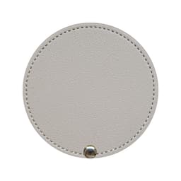 A round makeup mirror in a soft beige colour, featuring a textured finish and a metal clasp at the bottom.