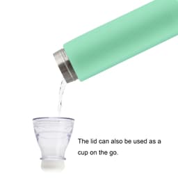 A drink bottle in mint green with a stainless steel finish, pouring into a transparent cup. It has a logo on the side.