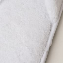 A pair of soft white hotel slippers featuring a plush texture and a branded logo on the side.