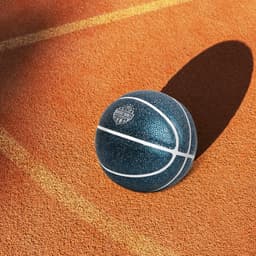 A blue mini basketball with a textured surface and white markings, resting on an orange court.