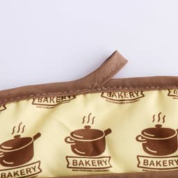A large quilted pot holder in brown and yellow with a patterned interior featuring cooking pots and a logo.