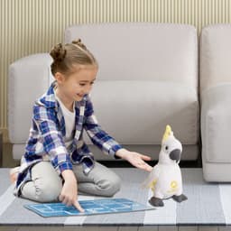 A child with a plaid shirt sits on a rug, holding a game board, next to a white and yellow cockatoo plush toy.
