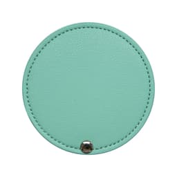 A round makeup mirror in mint green with a textured surface and a silver snap button.