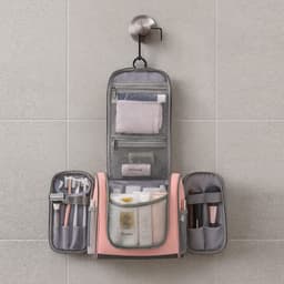 A travel storage bag in grey and pink, featuring compartments filled with toiletries and cosmetic items.