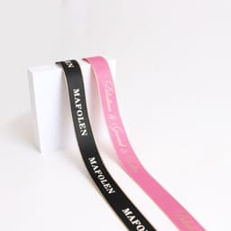 Two ribbons in black and pink, featuring gold-edged details and logos, arranged against a plain white background.