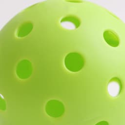 A bright green pickleball with multiple perforations, showcasing a smooth surface and spherical shape.