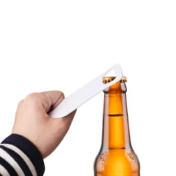 A drink bottle opener in hand, designed with a sleek, white appearance, positioned above a brown beer bottle.
