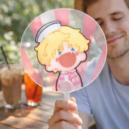 A transparent PVC hand fan featuring a cartoon character with blonde hair and a playful expression, held by a person.