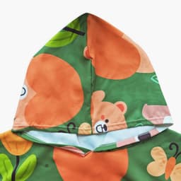 A hooded towel poncho featuring a green background with orange bears and floral patterns. It has a playful design.