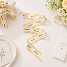 A satin narrow scarf featuring a white background with gold polka dots and a decorative edge, styled alongside floral arrangement.