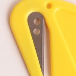 A yellow letter opener featuring a metal blade and a plastic handle, with a small hole at the top for hanging.