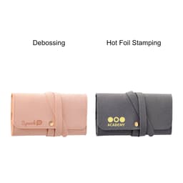 A synthetic leather jewellery bag in pink and grey, featuring a logo and a clasp closure.