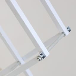 A close-up of a white metal frame with brackets and a connecting rod, designed for a backlit display.