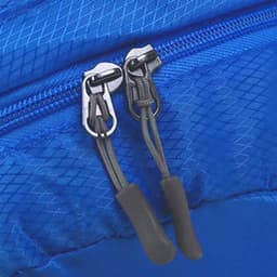A blue compressed bag featuring dual zippers with black pulls and a textured surface. The bag has a small logo.