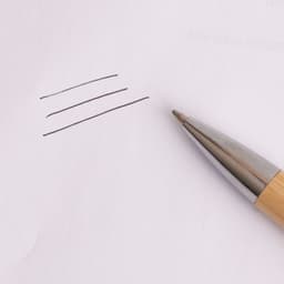 An Eco Bamboo Click Pen in natural bamboo with a silver tip, creating lines on white paper.