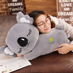 A soft grey koala plush toy with large eyes, featuring a branding logo, and a person hugging it.
