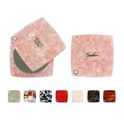 A pink acetate vanity mirror with a square design, featuring a reflective surface and a branding logo.