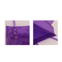 A purple PVC clear tote bag featuring snap fasteners and shoulder straps, with a glossy finish and a logo.