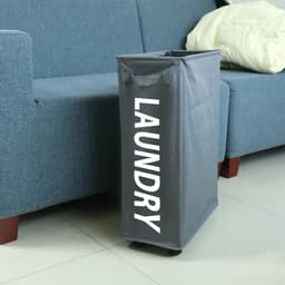 A grey laundry basket on wheels with handles, placed beside a sofa, featuring the word "LAUNDRY."