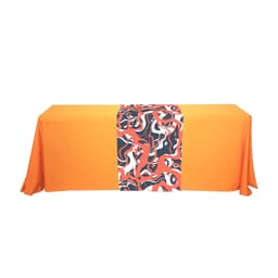 A large table runner featuring a vibrant abstract pattern in red, black, and white on an orange tablecloth.