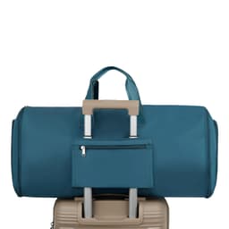 A teal duffel bag sits atop a beige suitcase, featuring a small zippered pocket on the front.