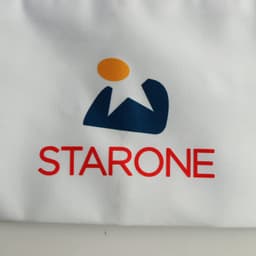 A white chef hat featuring a logo with blue and orange elements, alongside the word "STARONE" in red.