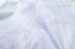 A close-up of a light-coloured, patterned fabric showcasing stitching details of a V-neck shirt.