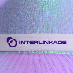 Iridescent cowboy hat in shades of purple and pink, featuring a white band with a logo.