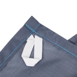 A close-up of a grey picnic blanket featuring a white handle and blue stitching, with a logo present.