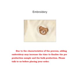A close-up of a cream coloured fabric featuring a brown teddy bear embroidery.
