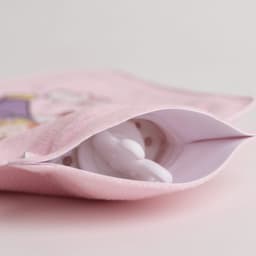 A hot water bottle in white, nestled inside a pink plush cover featuring a cute design.