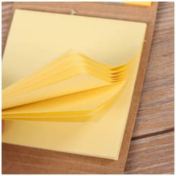 A set of yellow mini sticky notes with a brown holder, displaying stacked notes ready for use.