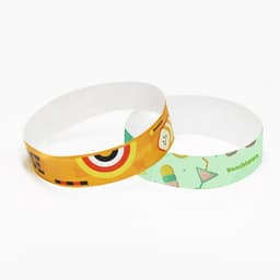 Two disposable Tyvek wristbands featuring vibrant colours and designs, one with a playful motif and the other with a beach theme.