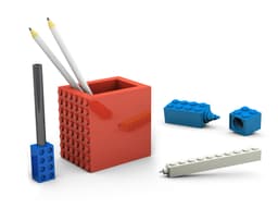 A red pen pot with two pencils, a black pen, and assorted blue and white building block pieces.