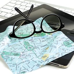 A microfibre cleaning cloth featuring a city map design, placed on a tablet and smartphone, alongside black glasses.