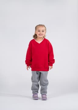 A red kids v-neck fleece jumper displayed on a smiling child wearing grey pants and purple shoes.