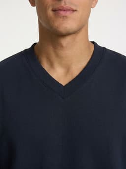 A navy V-neck fleece jumper with a relaxed fit, featuring a subtle logo on the chest.