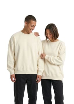 A cream-coloured oversized crew neck fleece worn by a man and a woman, both smiling. The image features a logo.