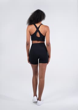 A pair of women's high-rise legging shorts in black, modelled from the back, featuring a logo on the waistband.
