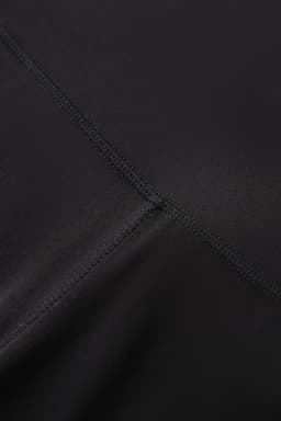 A close-up of black women's high rise full length leggings, featuring smooth fabric and stitching details.