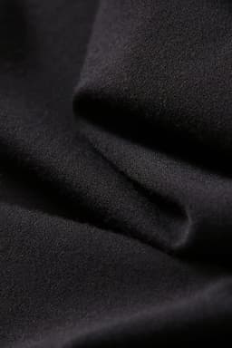 A close-up of soft, black fabric, showcasing the texture and drape suitable for leggings.