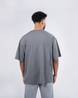 A grey unisex oversized tee displayed from the back, featuring a relaxed fit and short sleeves.