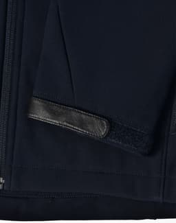 A navy softshell jacket featuring a sleek design with a leather patch on the sleeve. Includes a logo.