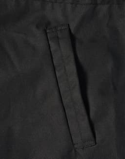 A close-up of a black fabric featuring a stitched pocket on a jacket. The material appears durable and textured.