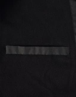 A close-up of a black long line stadium jacket featuring a sleek design and a pocket. The jacket has a branding logo.